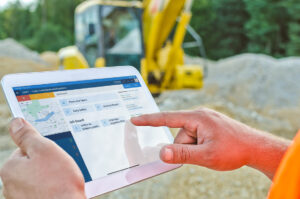 Construction worker using the Tractics foreman app on a tablet to view project dashboard tools and documents at a jobsite.a