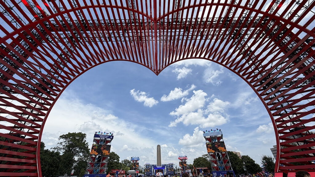 Kansas City’s FIFA Fan Festival viewed through a large red heart installation, with the Liberty Memorial in the distance.