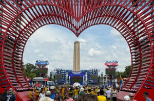 Fans gather at the FIFA Fan Festival in Kansas City beneath a heart-shaped installation, with the Liberty Memorial in the background.