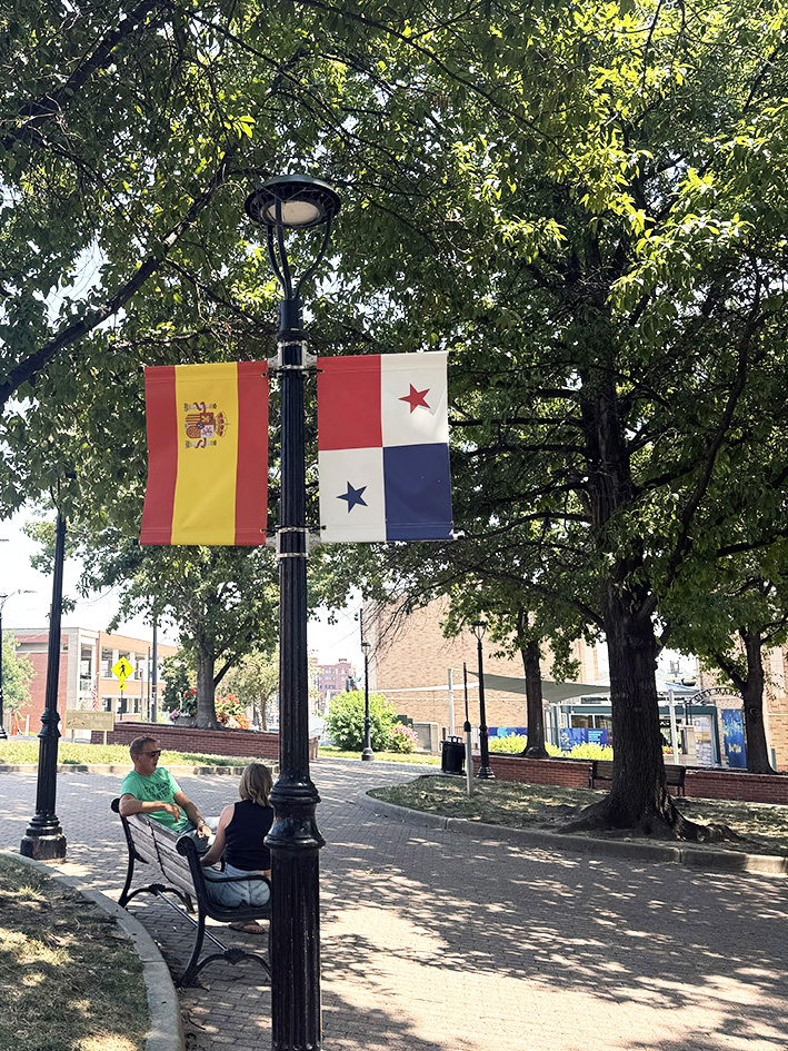 Tractics CEO sits on a bench in Kansas City’s River Market beneath international flags displayed during the 2026 World Cup.