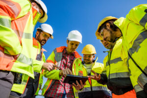 Construction crew gathered around a tablet while collaborating on a jobsite.